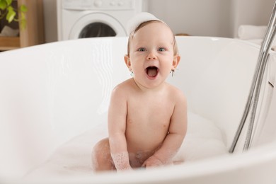Photo of Cute little baby bathing in tub at home