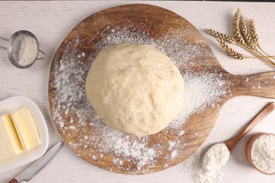 Photo of Fresh dough sprinkled with flour and other ingredients on white wooden table, flat lay