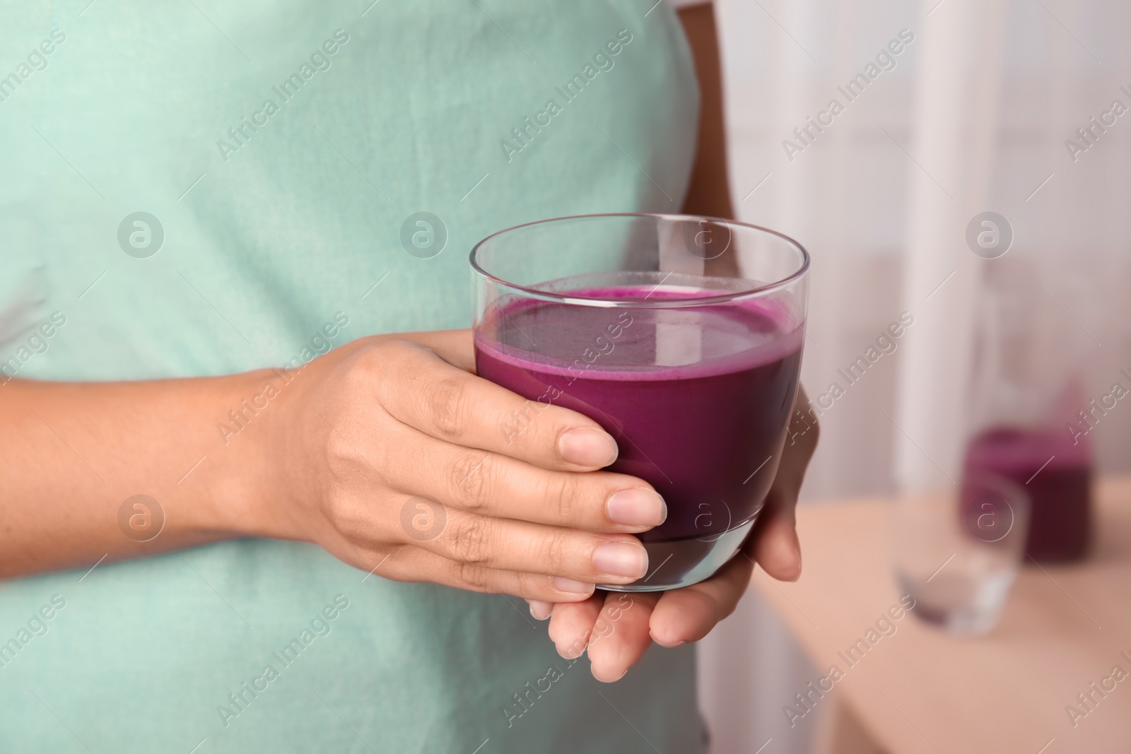 Photo of Woman holding glass of delicious acai juice, closeup