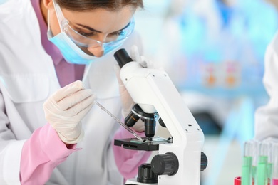 Young scientist working with microscope in laboratory, closeup. Chemical analysis