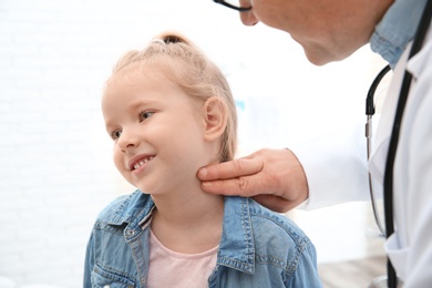 Doctor checking little girl's pulse with fingers in hospital