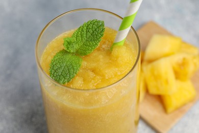 Photo of Glass of tasty pineapple smoothie with mint on light gray table, closeup