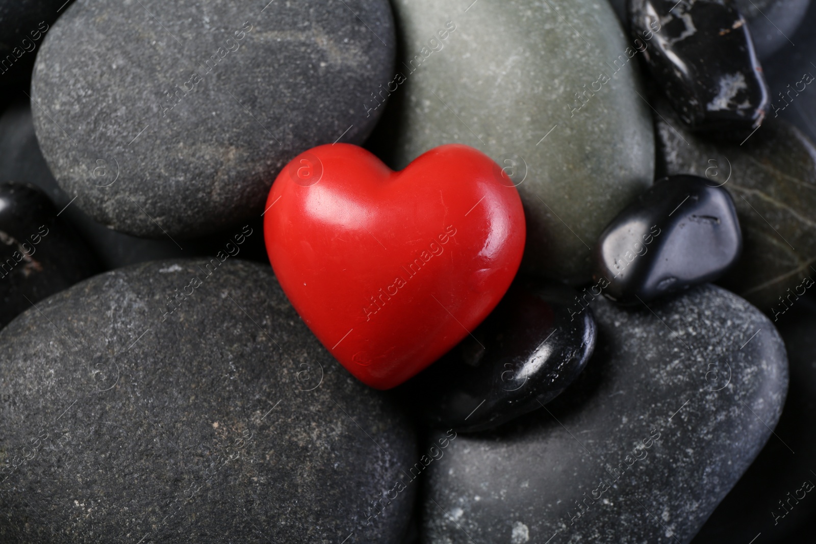 Photo of Red decorative heart on pebble stones, above view