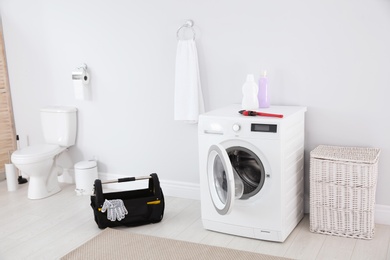 Photo of Plumber tools and washing machine in light bathroom