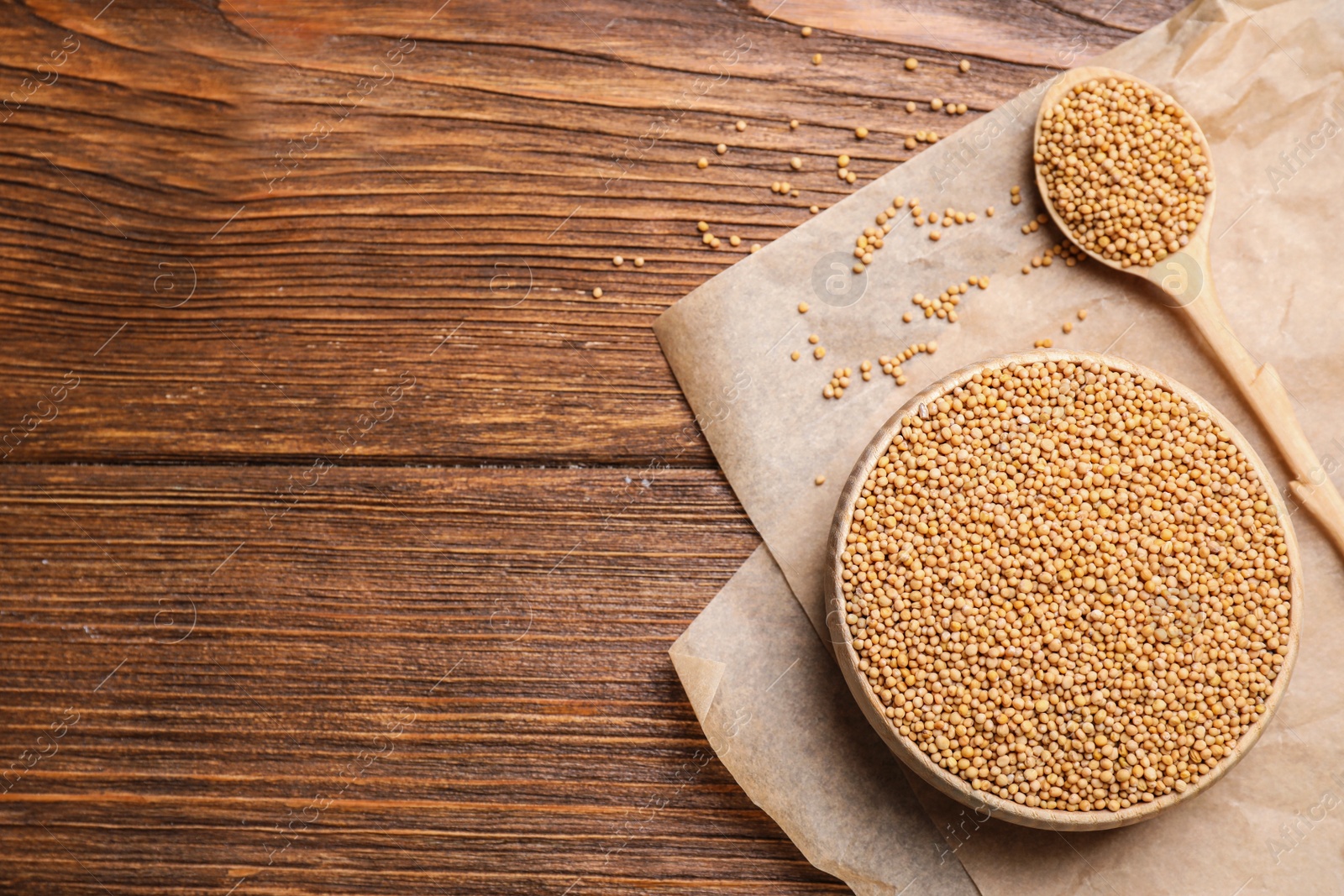 Photo of Mustard seeds on wooden table, flat lay. Space for text