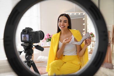 Photo of Fashion blogger with shoe recording video in dressing room at home, view through ring lamp