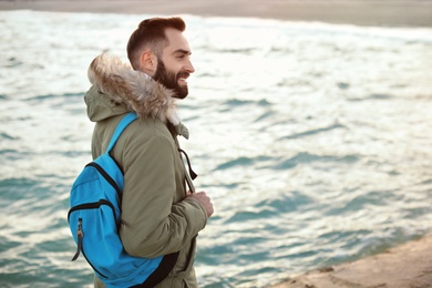 Stylish young man with backpack near sea