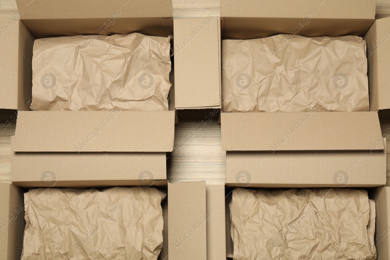 Photo of Many open cardboard boxes with crumpled paper on wooden floor, flat lay