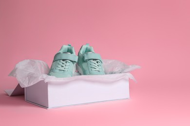 Photo of Pair of stylish sneakers in box on pink background