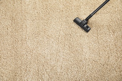 Removing dirt from beige carpet with modern vacuum cleaner, top view. Space for text