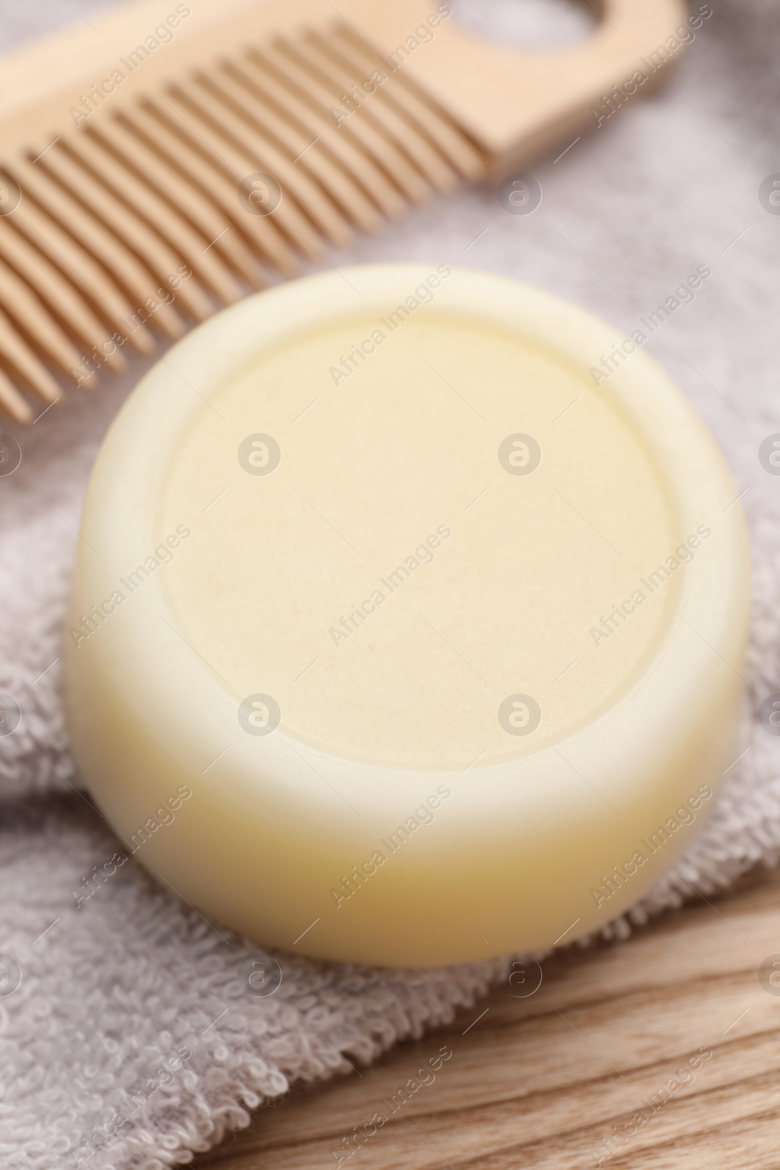 Photo of Solid shampoo bar and towel on wooden table, closeup