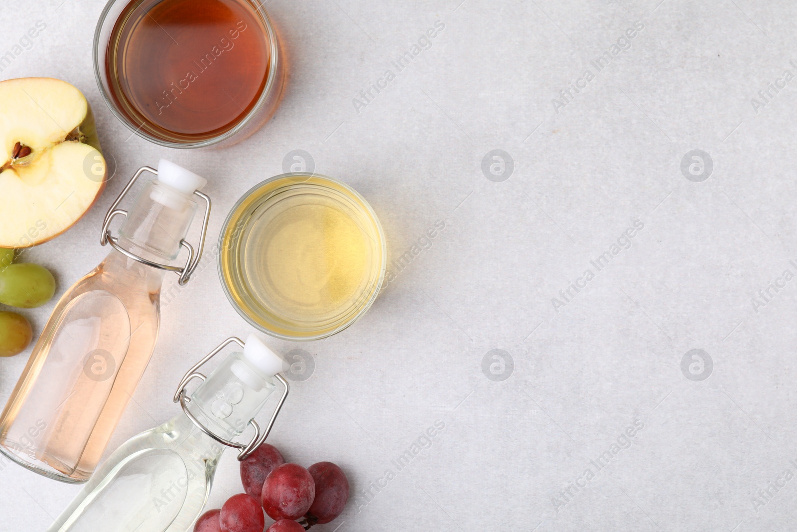 Photo of Different types of vinegar and ingredients on light table, flat lay. Space for text