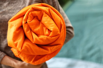 Photo of Woman holding rolled sleeping bag outdoors, closeup