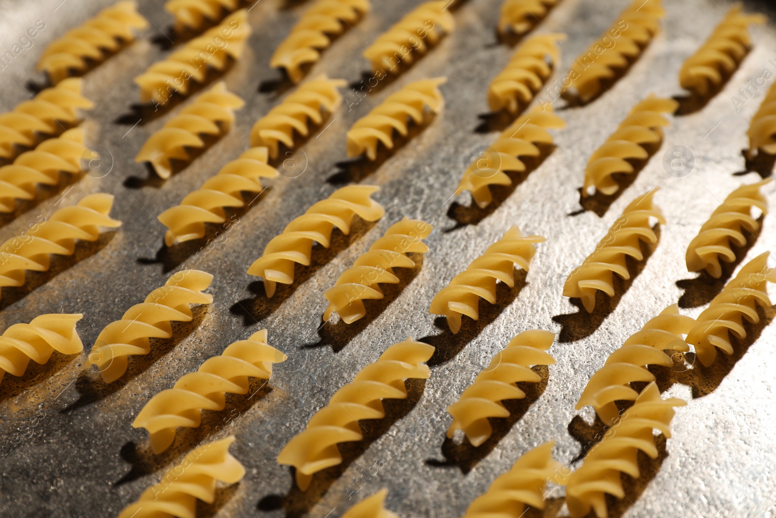 Photo of Uncooked fusilli pasta on grey table, closeup