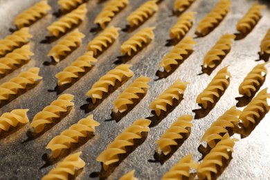 Uncooked fusilli pasta on grey table, closeup