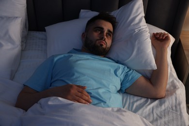 Photo of Frustrated man suffering from insomnia in bed