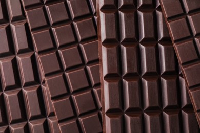 Photo of Many delicious dark chocolate bars as background, top view