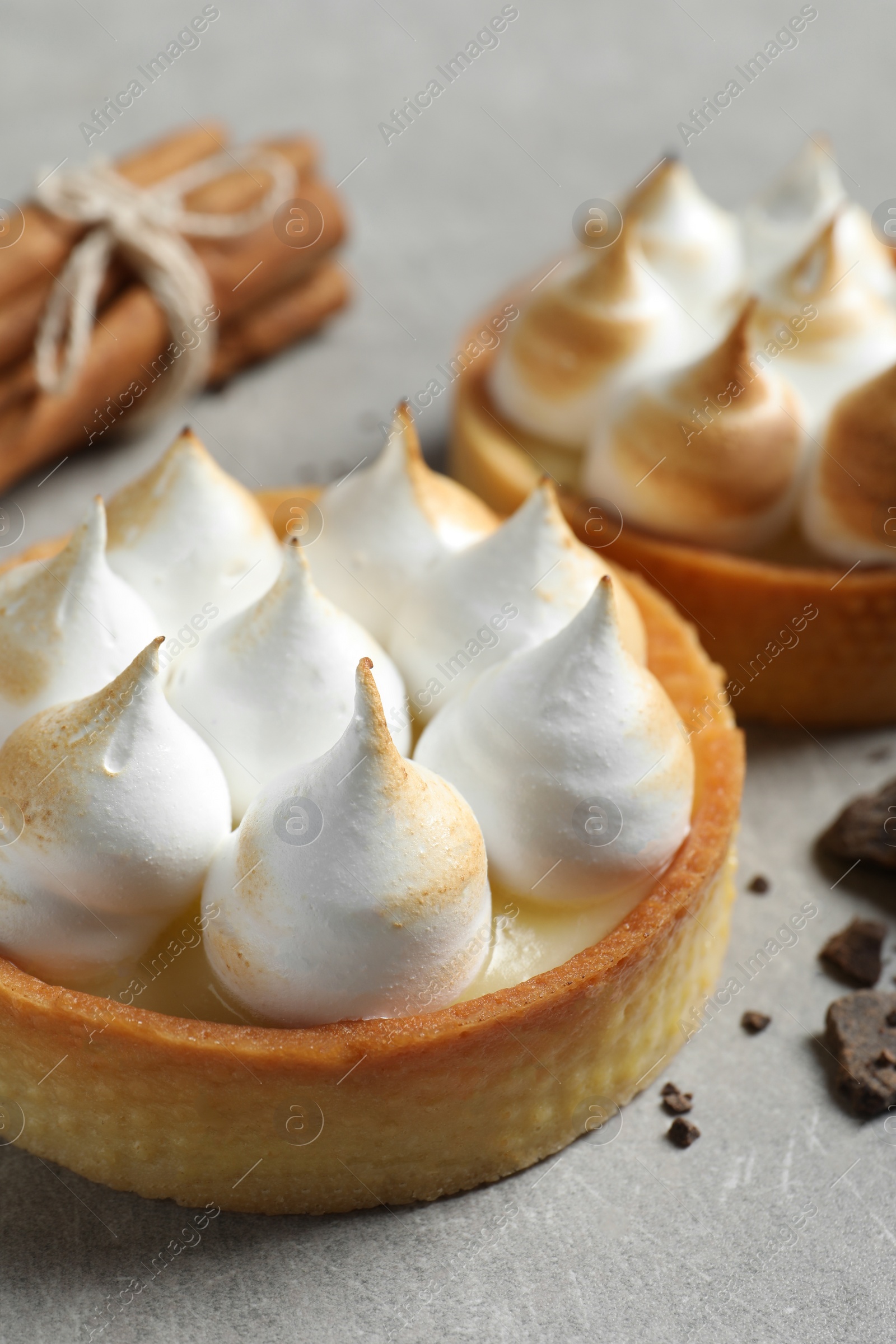 Photo of Tartlets with meringue on light grey table, closeup. Tasty dessert