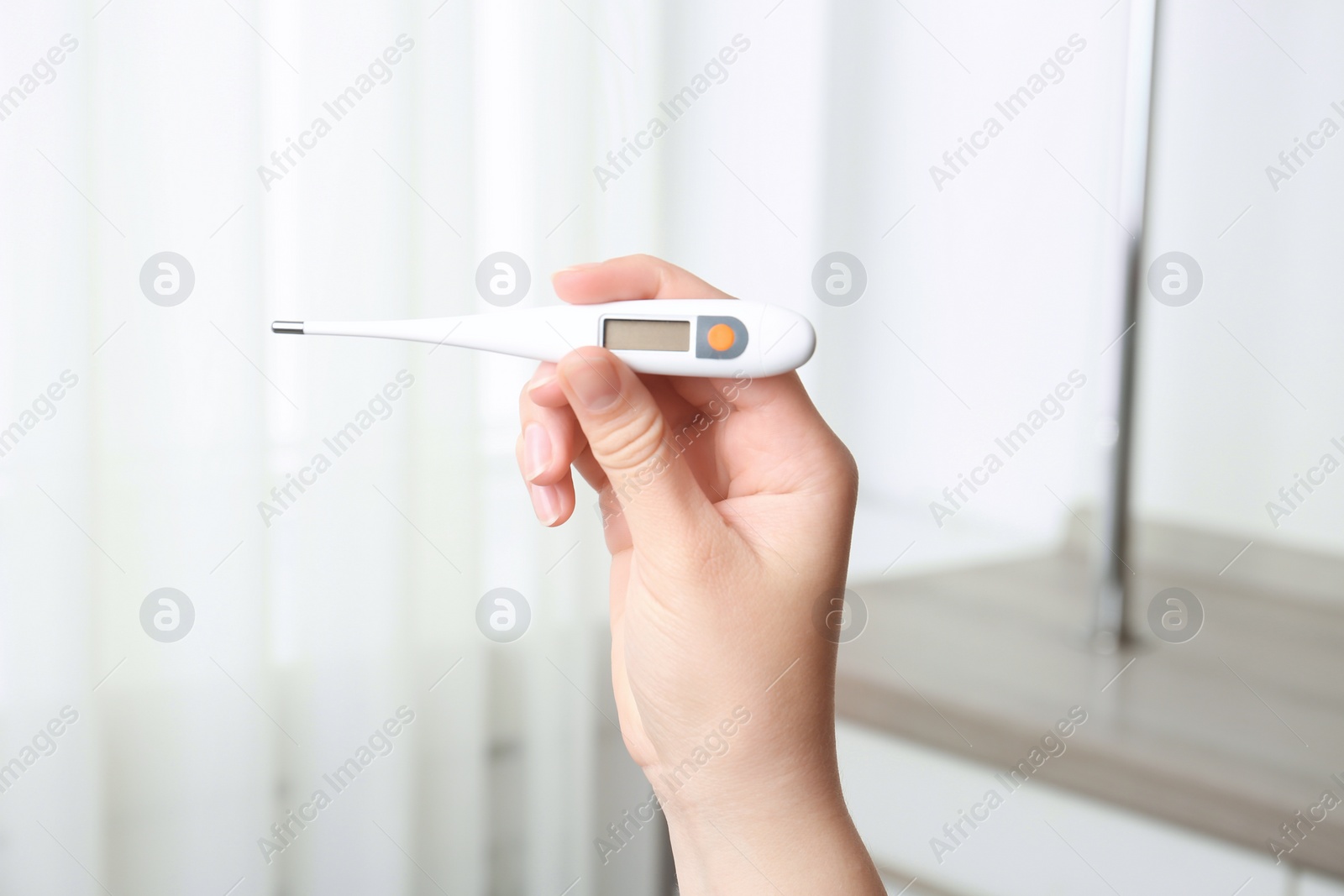 Photo of Woman with modern digital thermometer indoors, closeup