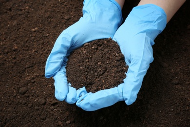 Photo of Scientist holding pile of soil above ground, closeup