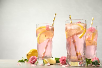 Photo of Delicious refreshing drink with rose flowers and lemon slices on light grey table