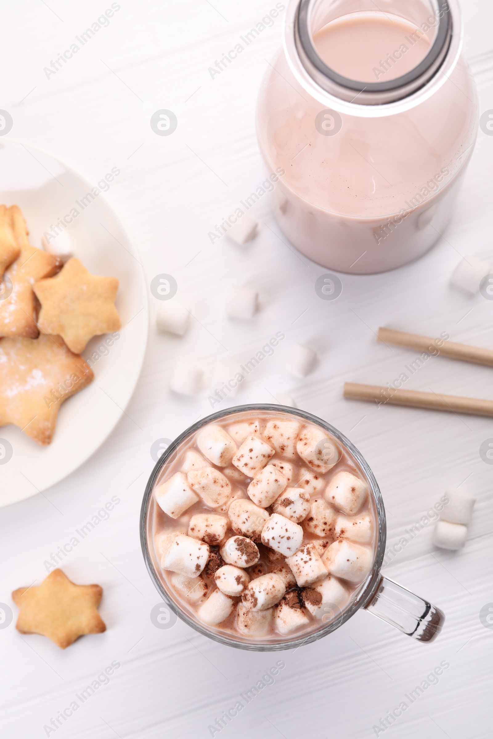 Photo of Cup of aromatic hot chocolate with marshmallows, cocoa powder and tasty cookies on white wooden table, flat lay