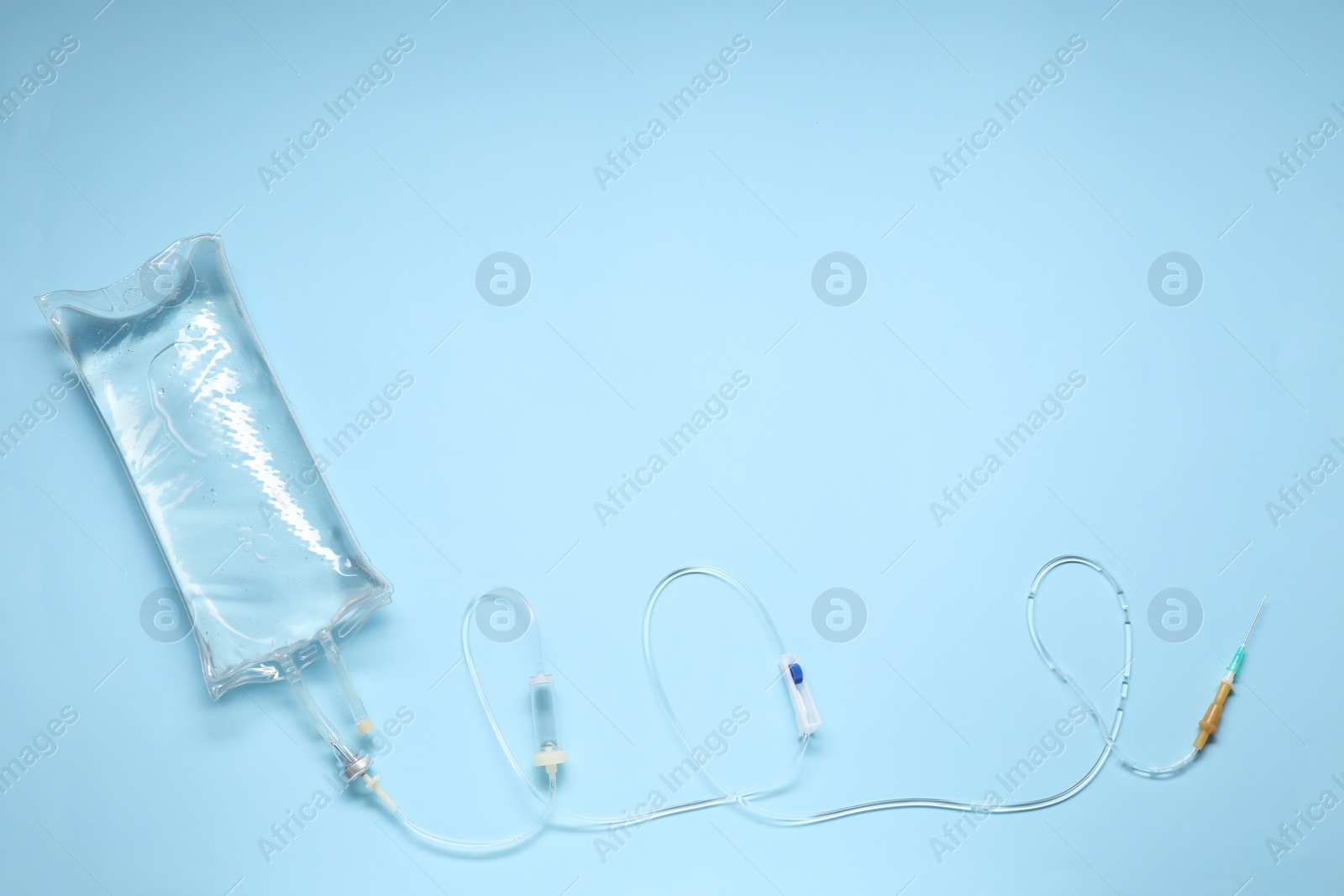 Photo of IV infusion set on light blue background, top view. Space for text