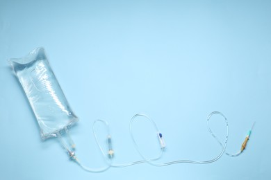Photo of IV infusion set on light blue background, top view. Space for text