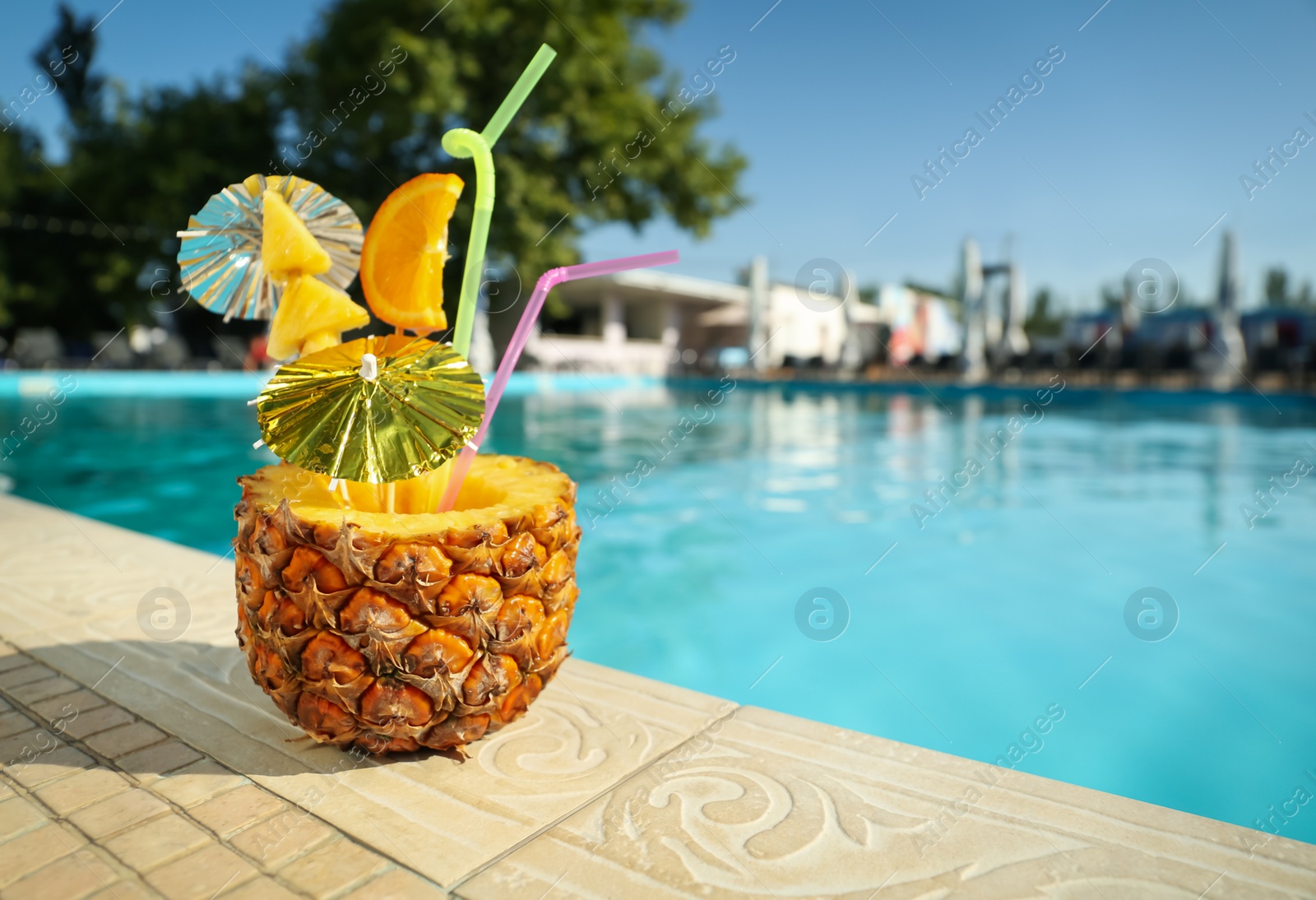 Photo of Tasty tropical cocktail on edge of swimming pool. Party drink