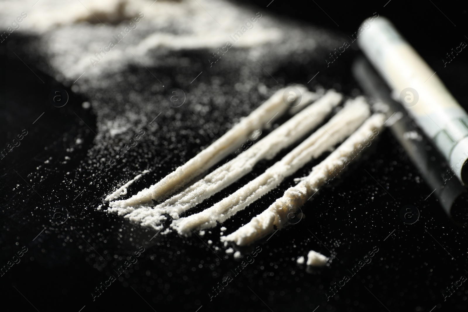 Photo of Drug addiction. Cocaine and rolled dollar banknote on black table, selective focus