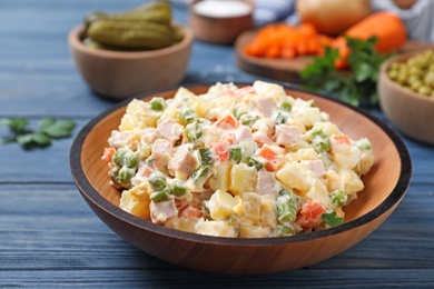 Photo of Delicious salad Olivier on blue wooden table