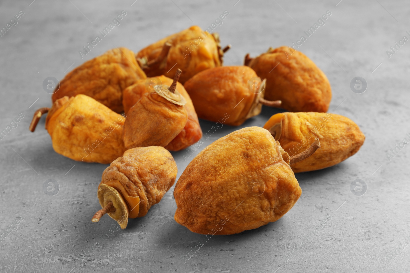 Photo of Many tasty dried persimmon fruits on light grey table