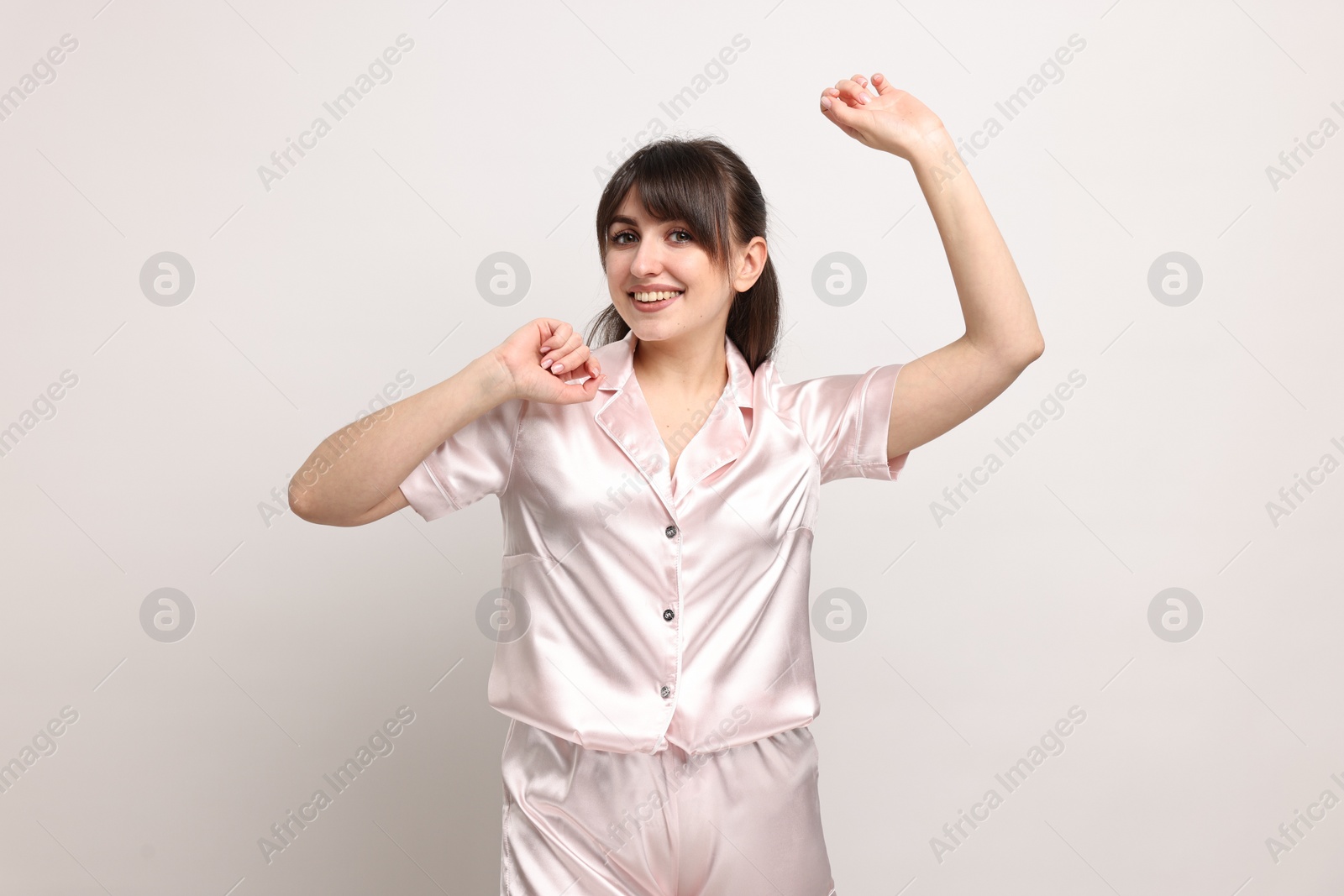 Photo of Happy woman in pyjama on light grey background