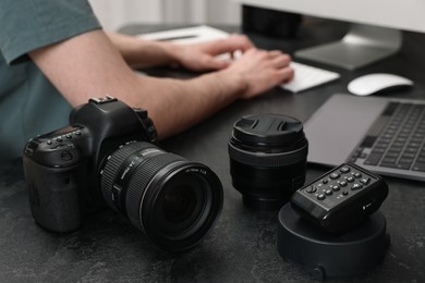 Camera on dark table, closeup. Photographer working with computer indoors, selective focus