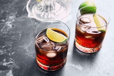 Photo of Glasses of cocktail with cola, ice and cut lime on marble background