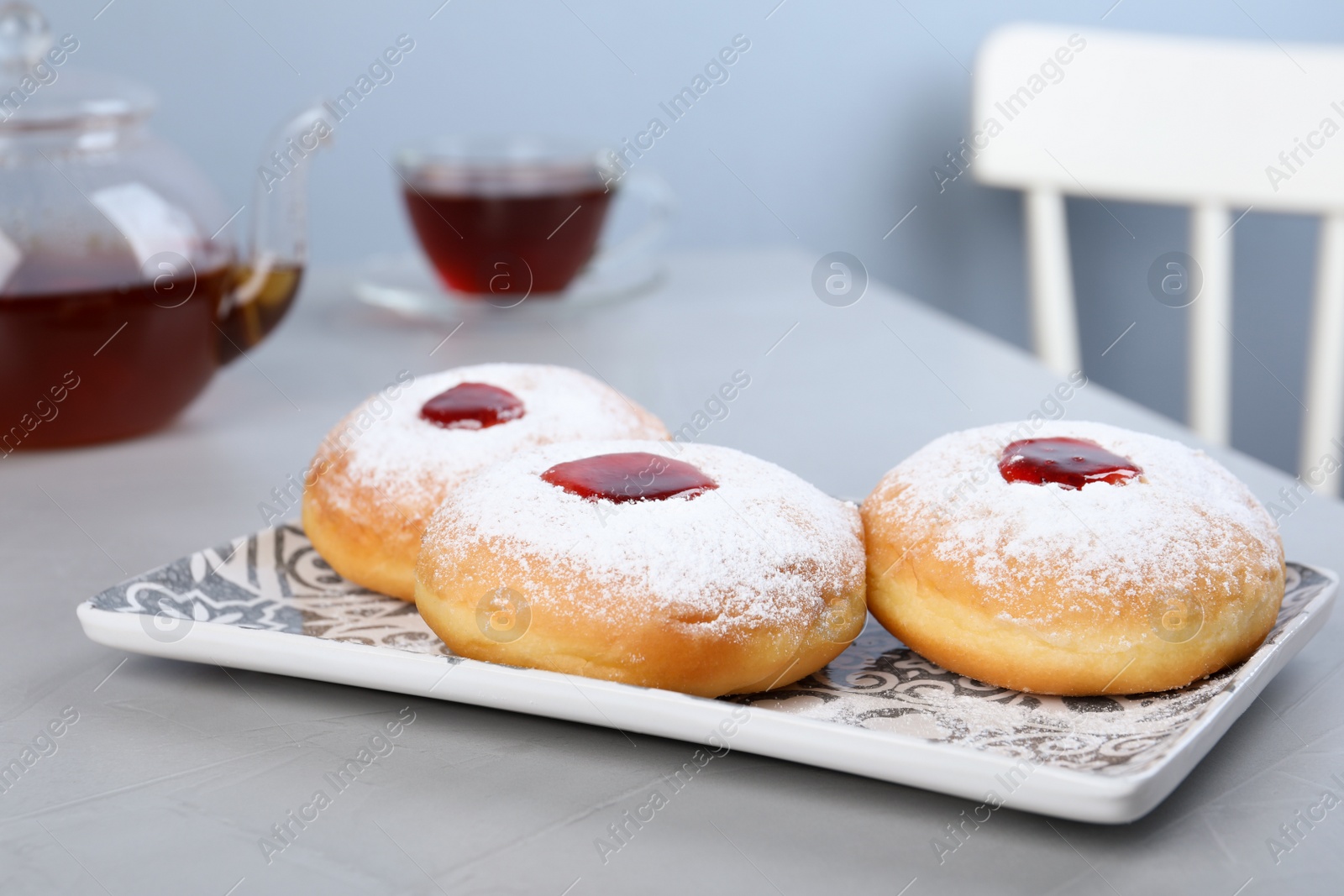 Photo of Hanukkah doughnuts with jelly and sugar powder served on grey table
