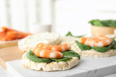 Photo of Puffed rice cakes with shrimps and basil on board, closeup