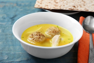 Photo of Bowl of Jewish matzoh balls soup on color wooden table