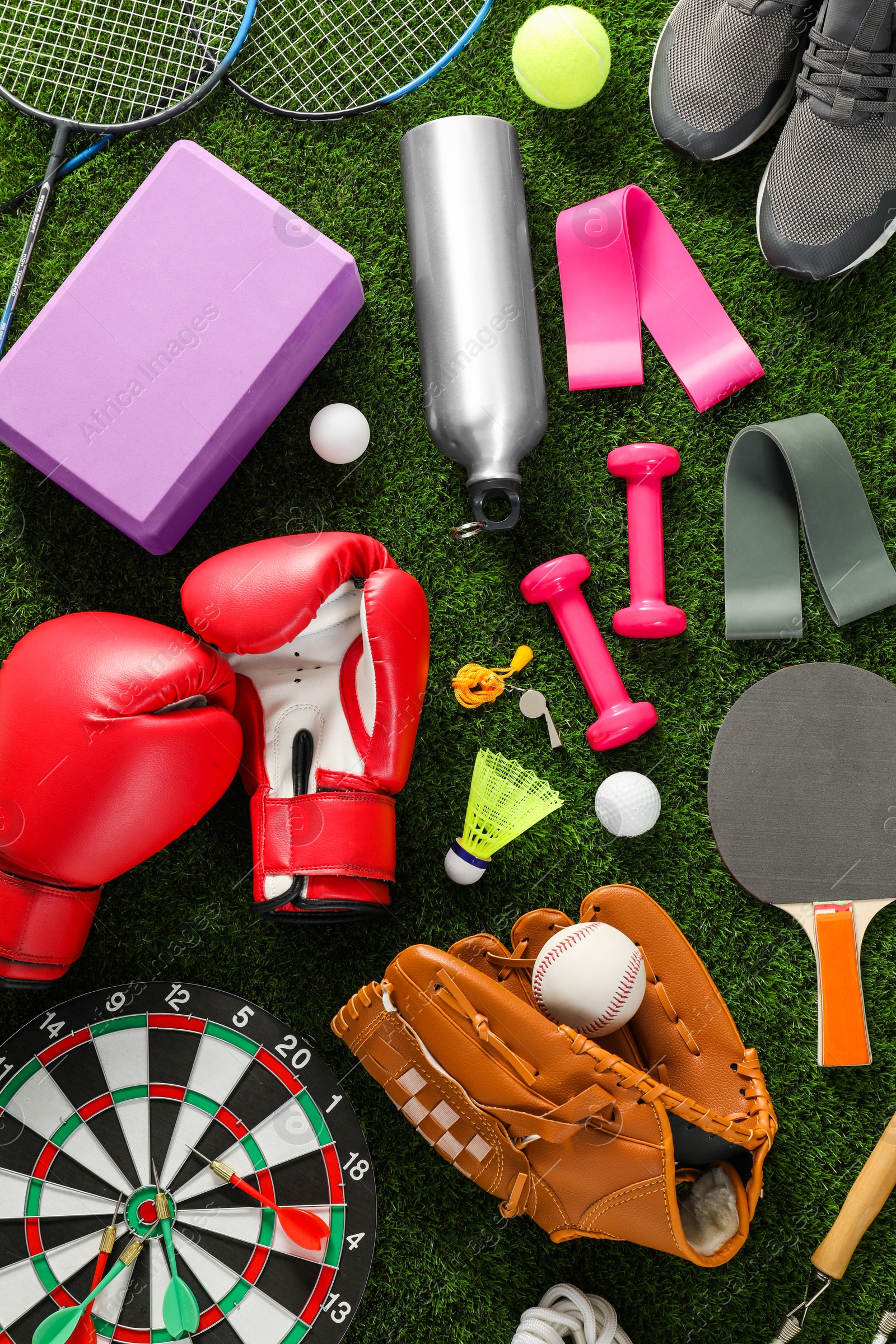 Photo of Different sport equipment on green grass, flat lay