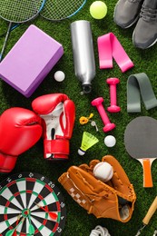 Photo of Different sport equipment on green grass, flat lay