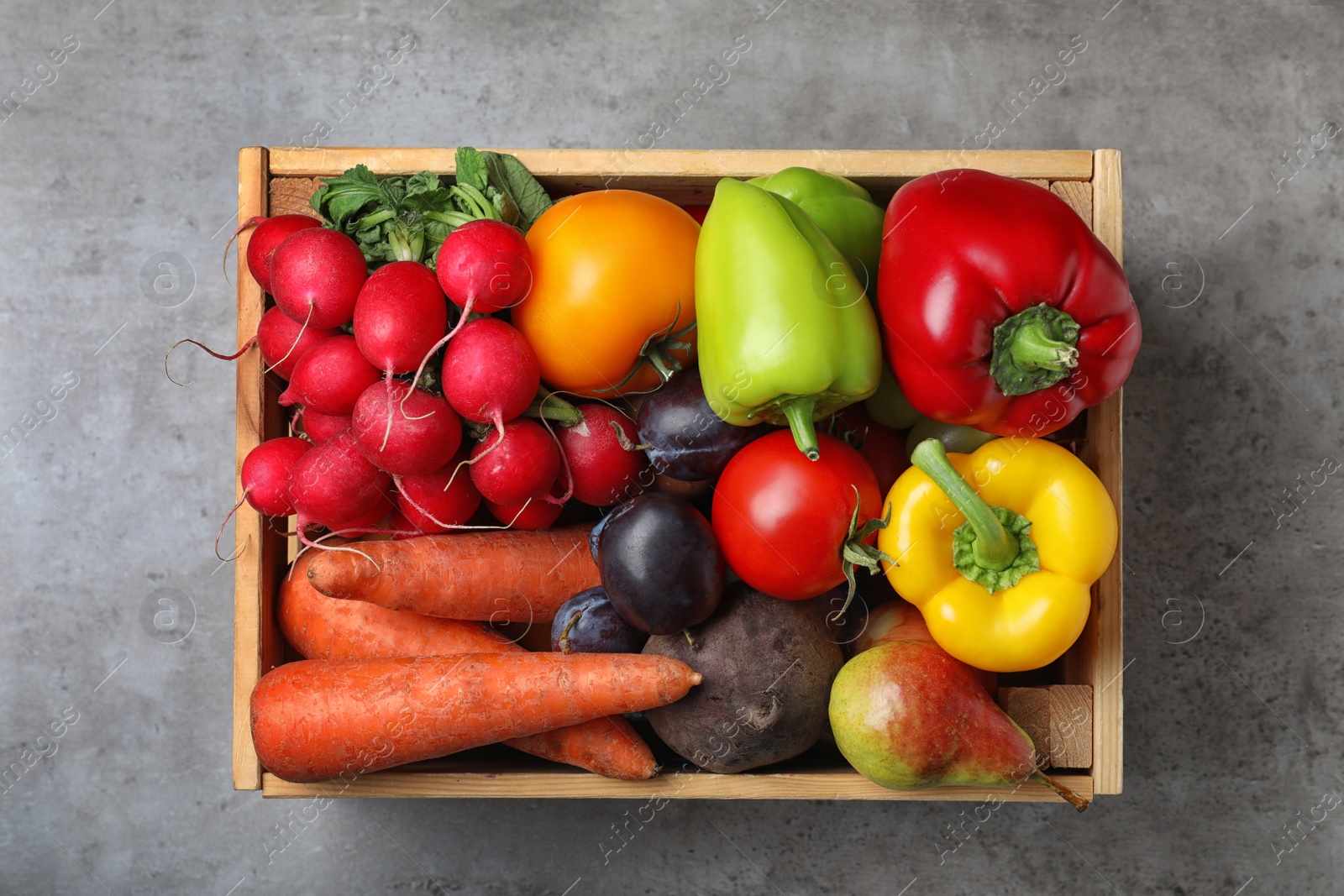 Photo of Wooden crate full of different vegetables and fruits on grey table, top view. Harvesting time