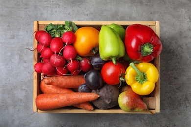 Photo of Wooden crate full of different vegetables and fruits on grey table, top view. Harvesting time