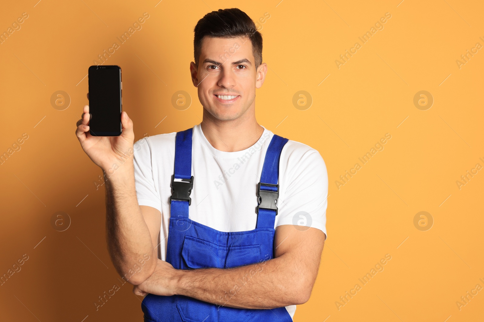 Photo of Repairman with modern smartphone on orange background