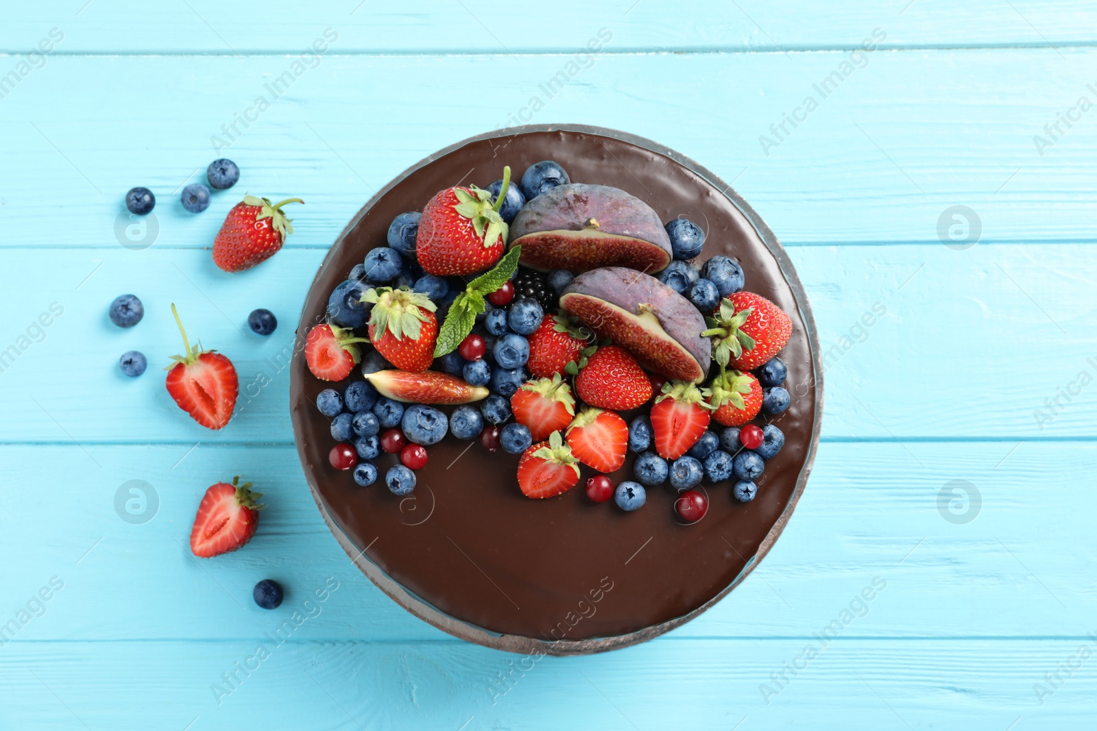 Photo of Fresh delicious homemade chocolate cake with berries on wooden table, flat lay