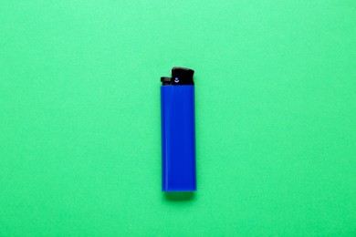 Photo of Stylish small pocket lighter on green background, top view