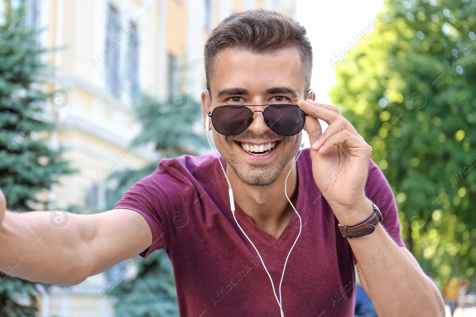 Photo of Young man in sunglasses taking selfie outdoors