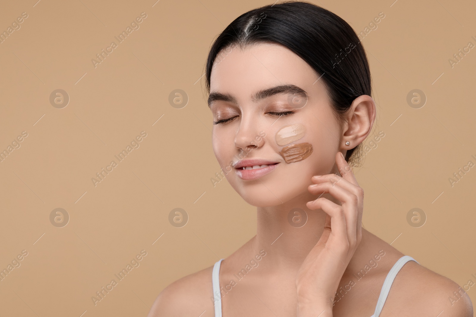 Photo of Teenage girl with swatches of foundation on face against beige background. Space for text