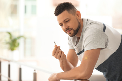 Man with nicotine patch and cigarette indoors. Space for text