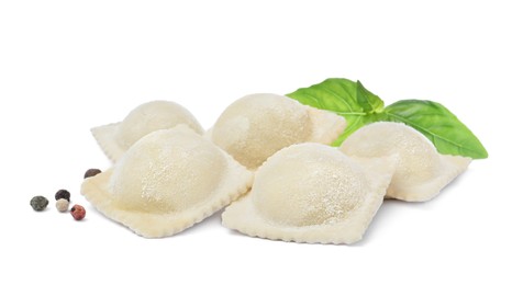 Photo of Uncooked ravioli, basil and peppercorns on white background