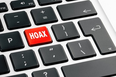 Red button with word Hoax on laptop keyboard, closeup